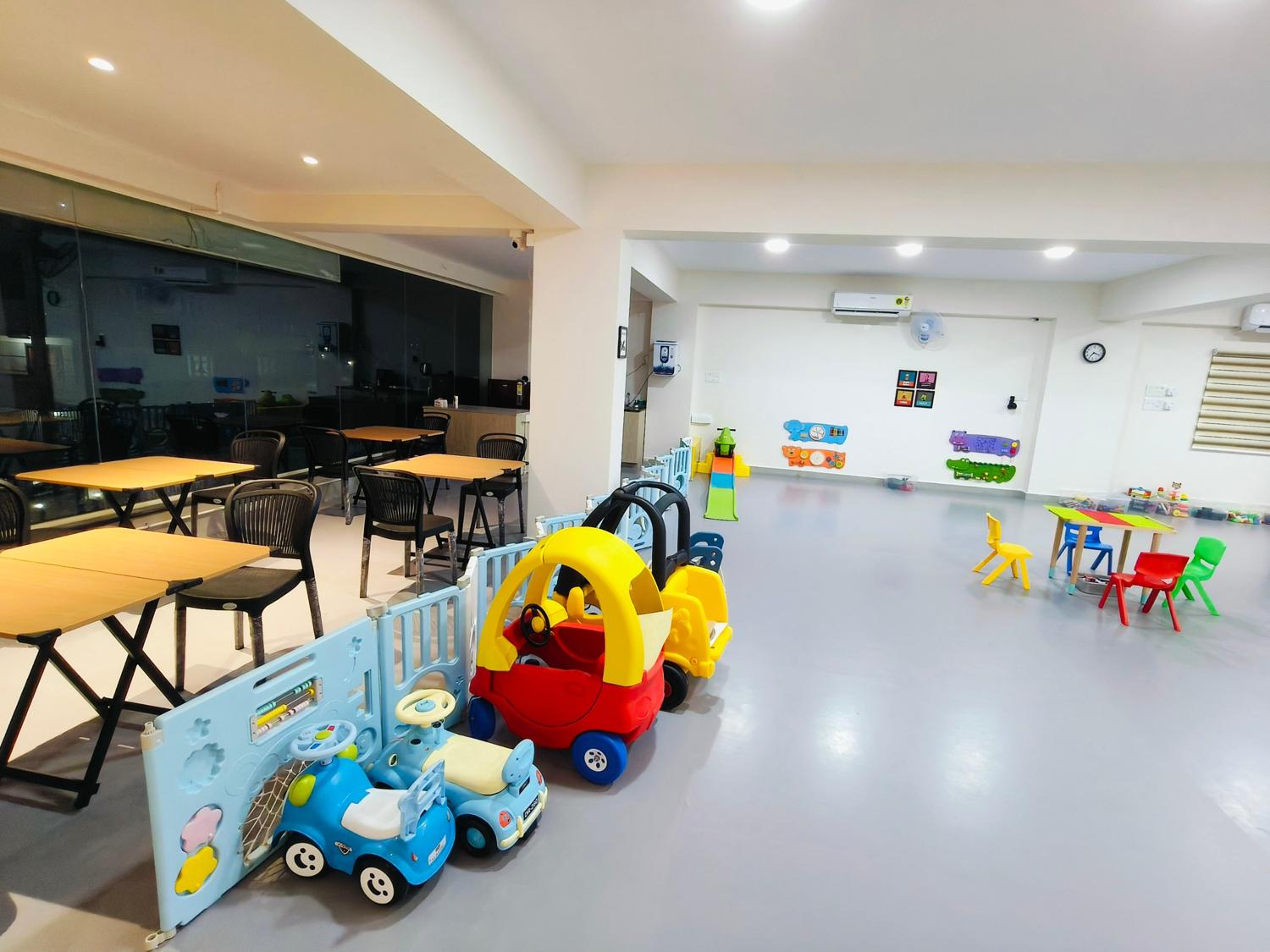 Open play area with ride-on cars, toddler slide and activity walls